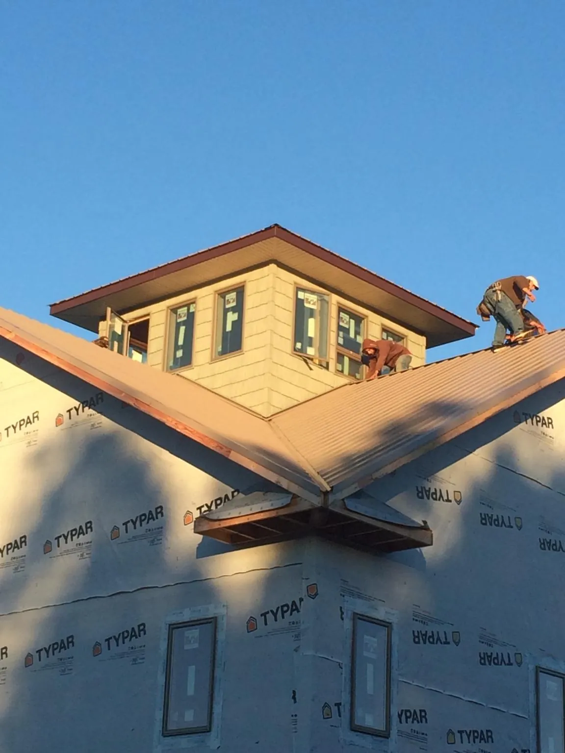 Roofers working around a rooftop cupola on a new metal roof at sunset — Roof Waterproofing in Farmington by Roofing Brothers
